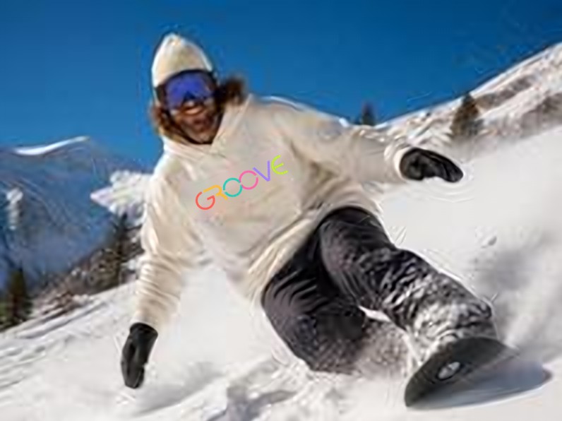 Snowboarder in a cream GROOVE hoodie and beanie carving down a sunny mountain slope