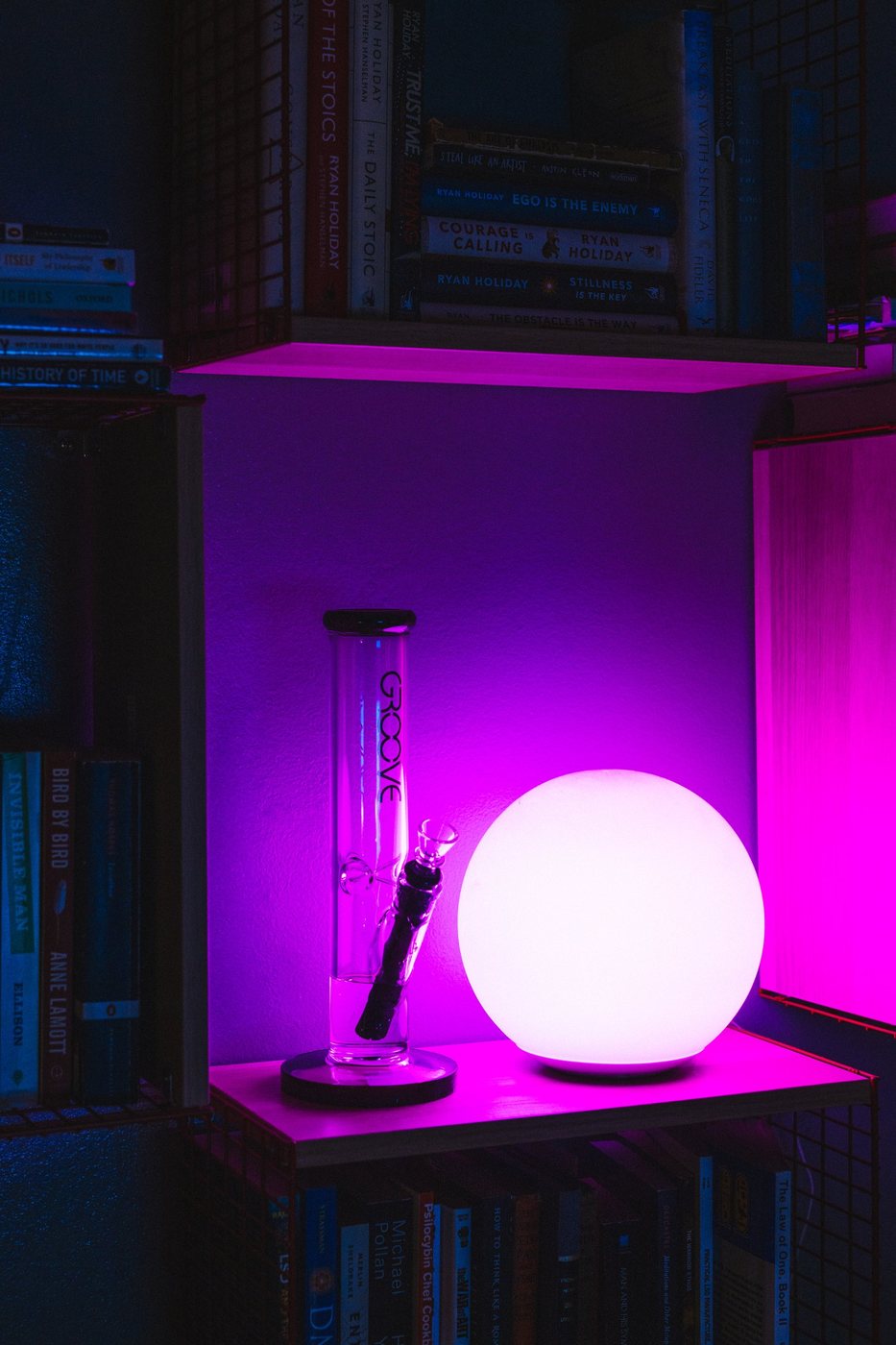GROOVE straight tube glass on a neon-lit bookshelf beside a glowing globe lamp